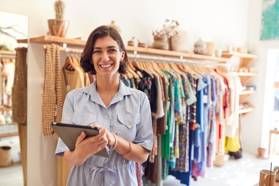 Una mujer utiliza una tablet en una tienda de ropa.
