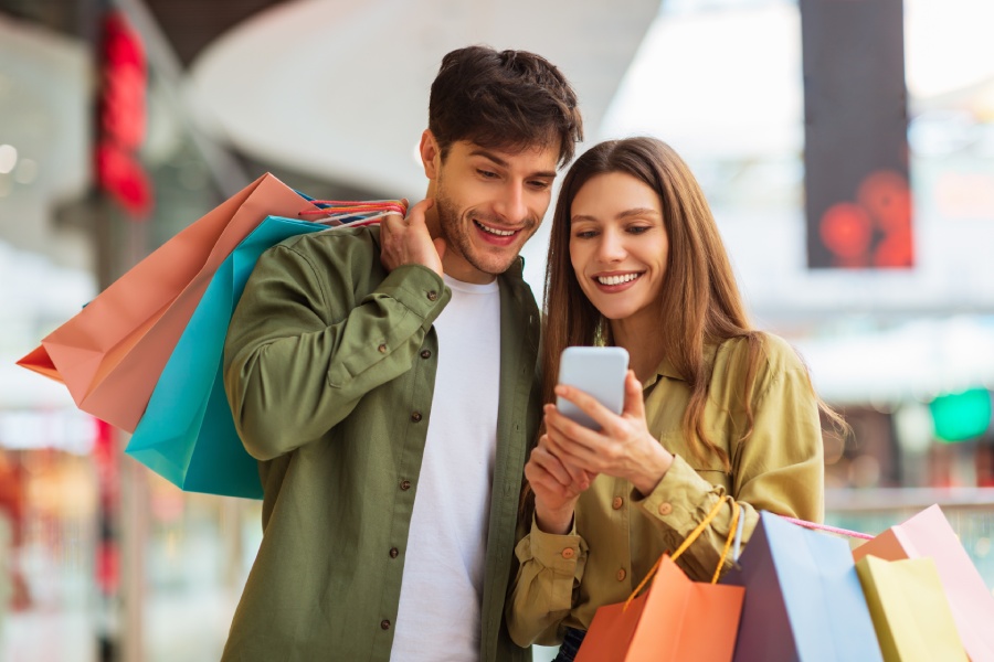 Una pareja mira una app del teléfono móvil mientras está de compras 