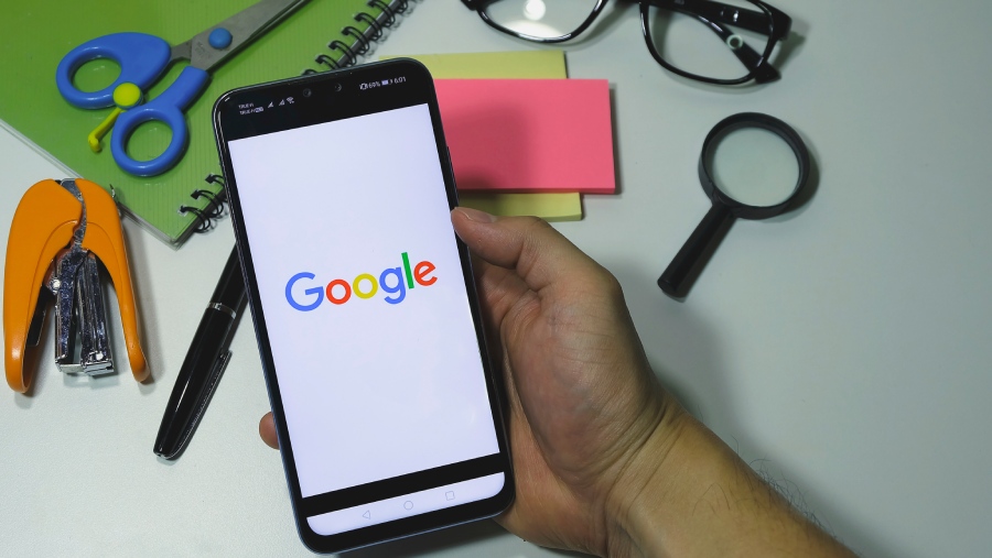 Una persona sujeta un móvil con el logo de Google