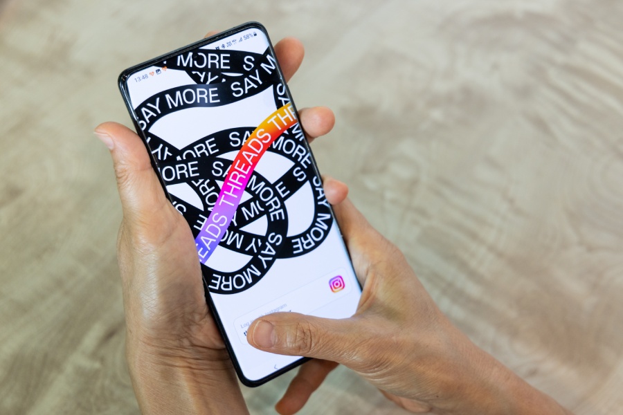 Manos sujetan un teléfono móvil con la app de Threads abierta